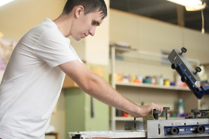 young man using a press for print-on-demand