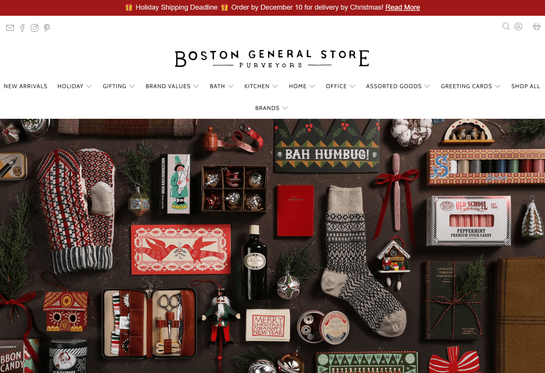 shopify general store: Flat lay of festive holiday gifts, including wool socks, mittens, greeting cards, chocolate bars, ornaments, a book, and candy, all arranged neatly on a brown background at Boston General Store.