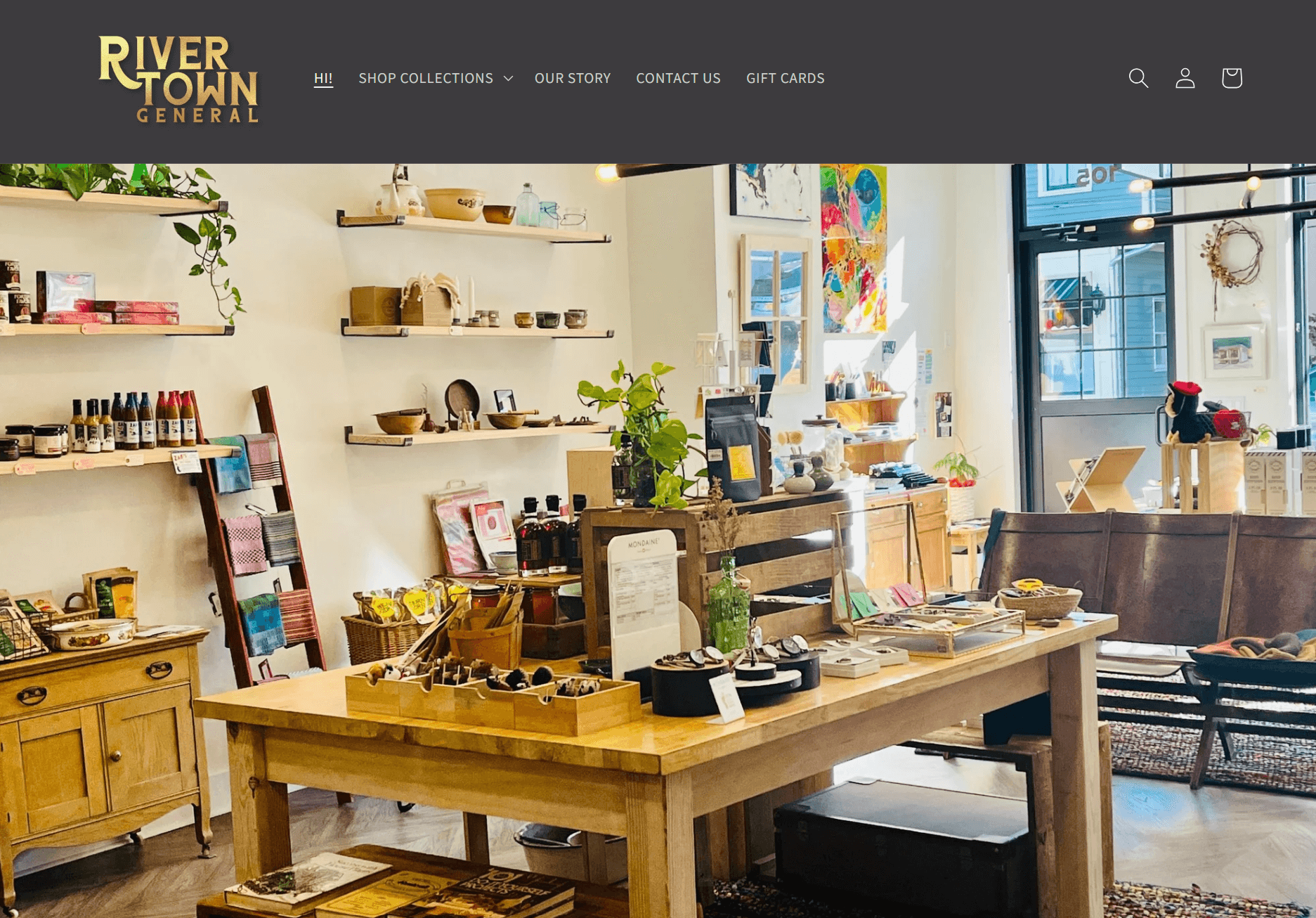 shopify general store: A cozy, well-lit shop interior with wooden shelves and tables displaying various goods, plants, and decor items. The front door is visible in the background, and a River Town General sign is at the top left.