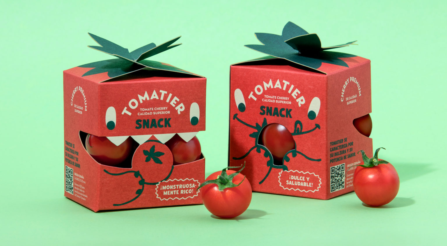 Customer acquisition strategies: Two red tomato snack boxes with playful monster faces and green leaf-shaped flaps are displayed on a green background, with fresh tomatoes visible inside and placed beside the packages.