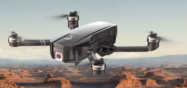 Most profitable products to sell online: A black quadcopter drone with a camera hovers above a desert landscape with red rock formations under a clear sky.