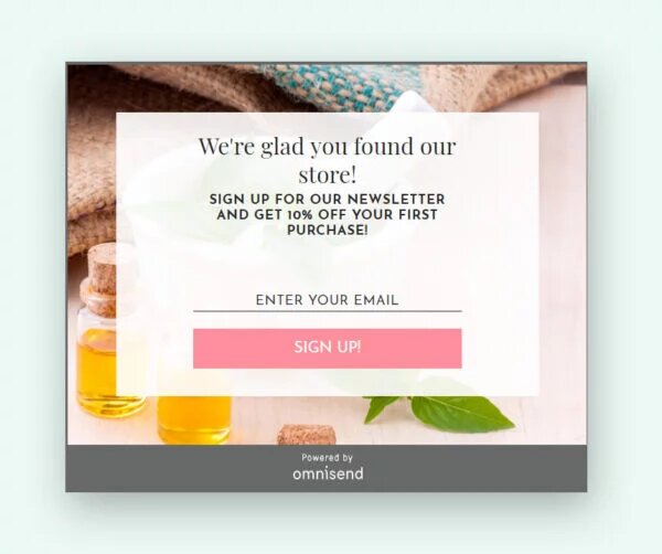 Email capture: Pop-up message offering 10% off first purchase for signing up for a newsletter, with a pink Sign Up! button. Small bottles, green leaves, and towels are visible in the background.