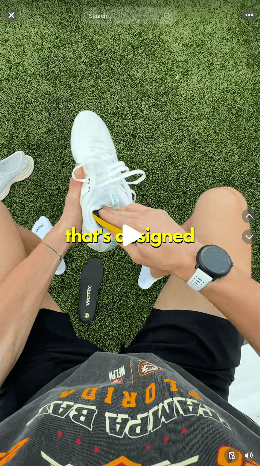Testimonial advertising: A person sitting on grass inserts a VKTRY insole into a white sneaker.