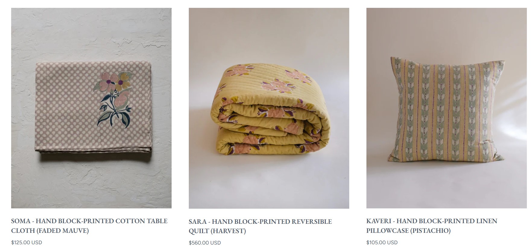 How to make money on Shopify: Three products are shown: a folded mauve tablecloth with a floral print, a folded yellow floral quilt, and a square pillowcase with vertical striped and floral patterns in pastel shades.