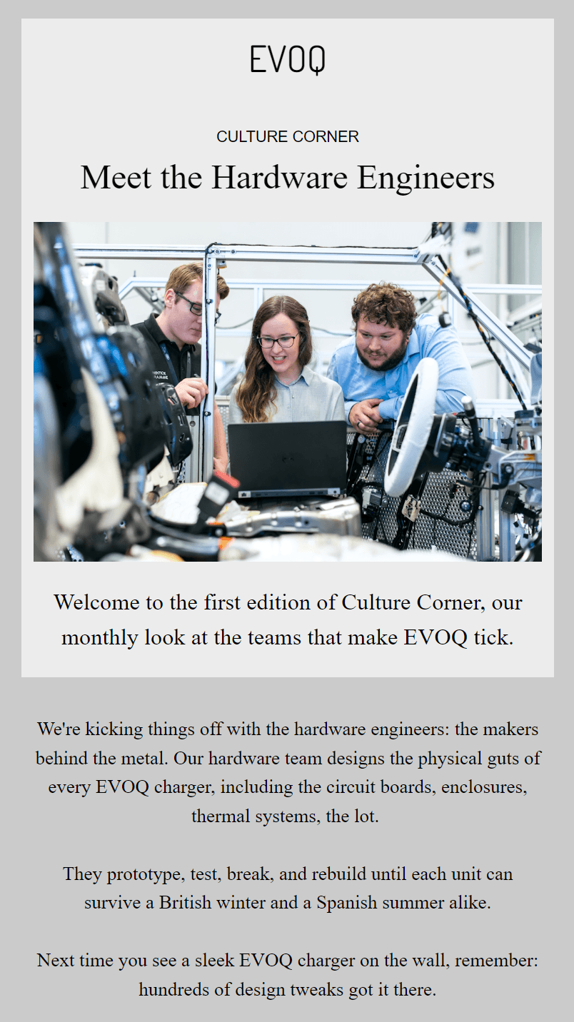 Company newsletter: Three engineers work together at a desk surrounded by EV charger parts and computer monitors. The scene captures a collaborative workspace with cables, tools, and technical equipment visible.