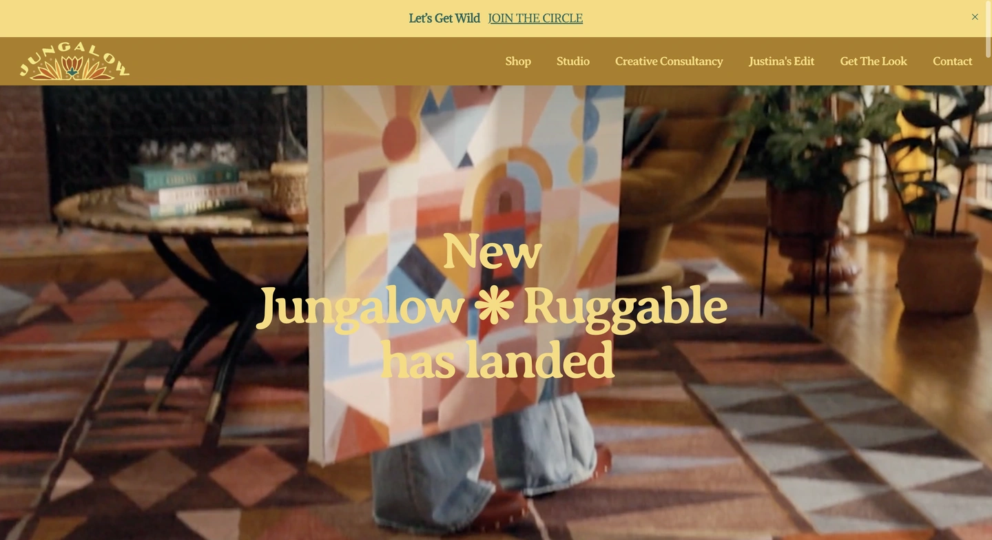Person holding abstract art stands on a patterned rug in a living room; text reads New Jungalow Ruggable has landed..