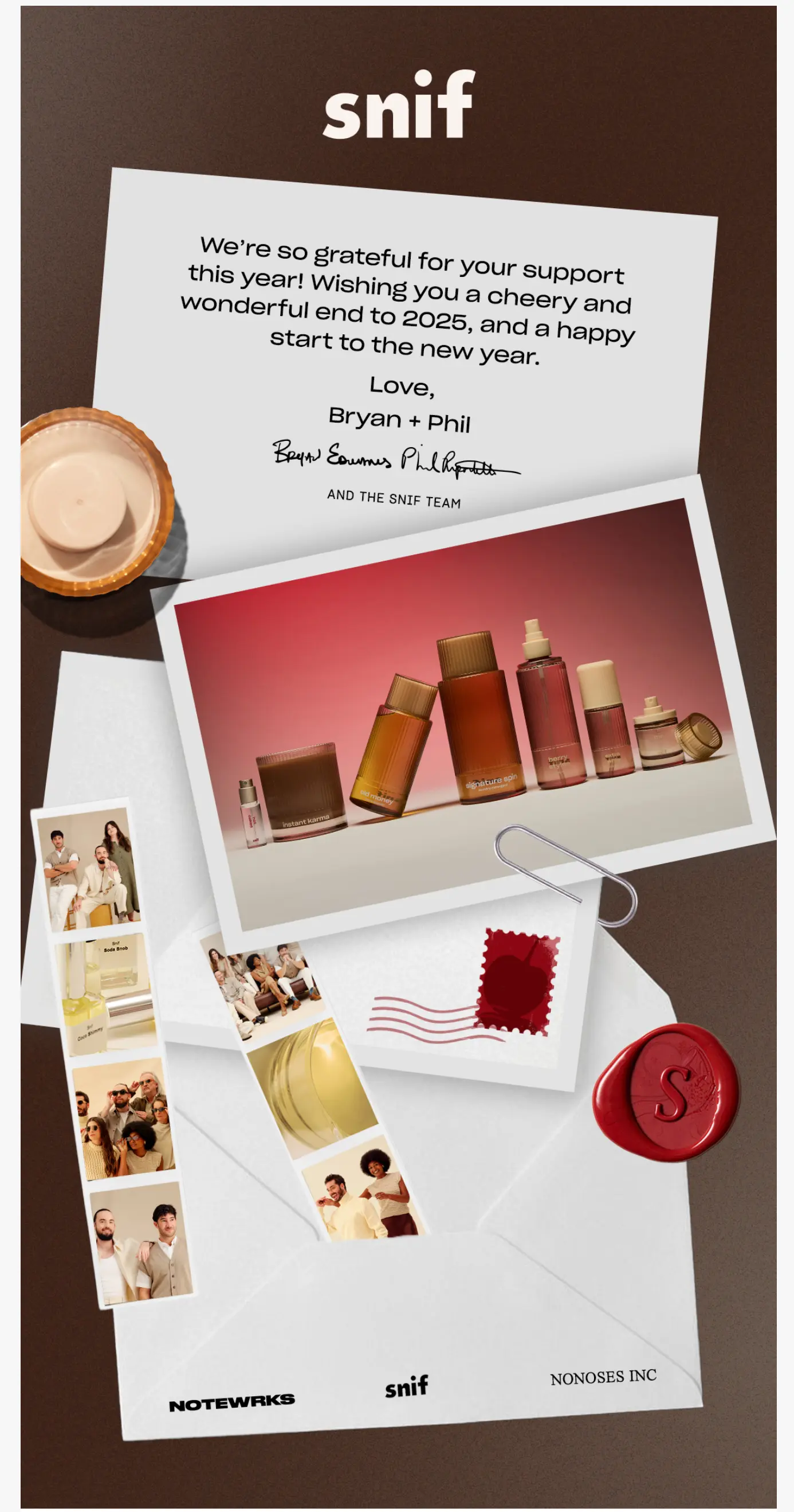 A flat lay of a holiday card, perfume bottles, photos, a wax seal, and stationery on a brown background.
