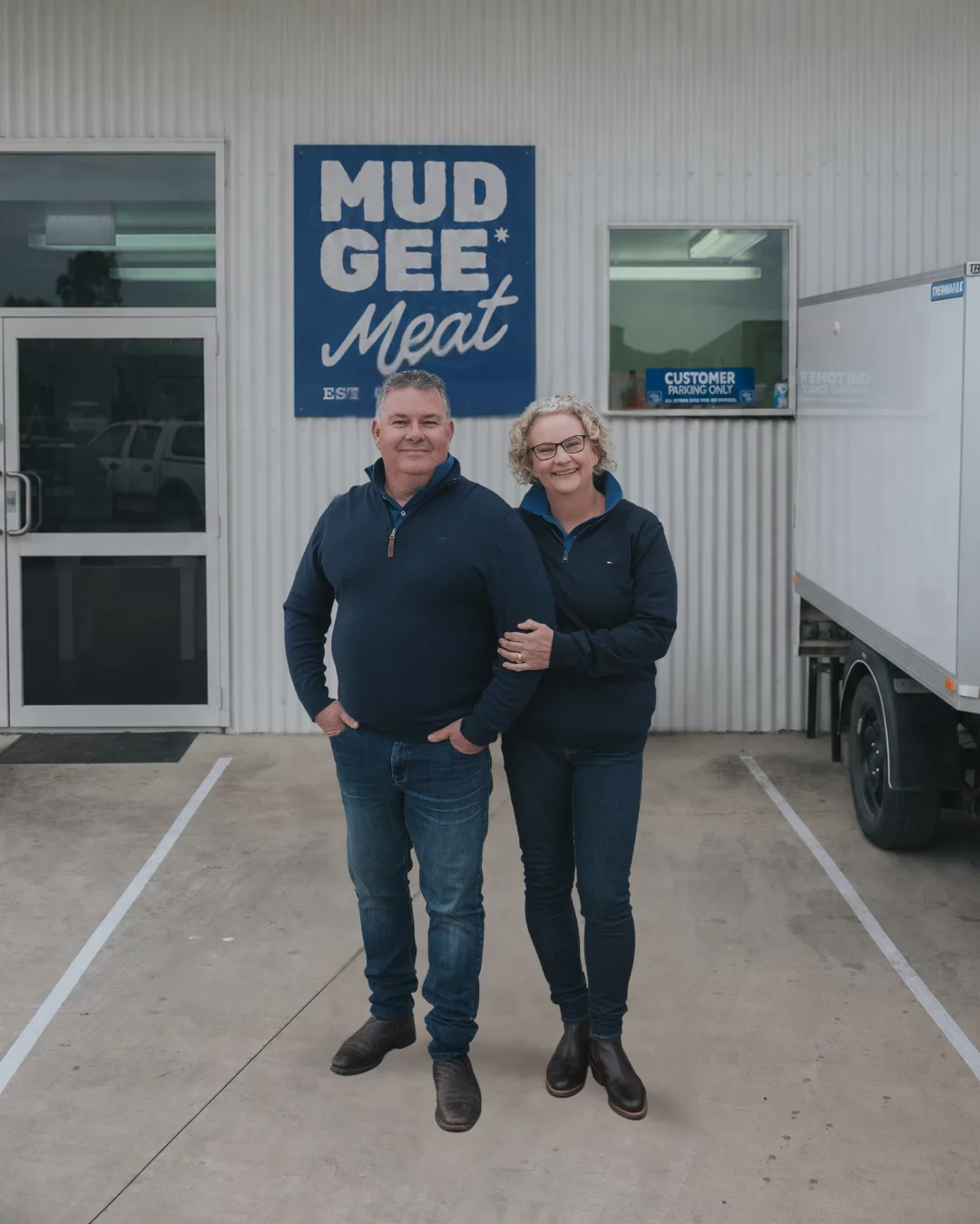 Michael and Carolyn Emeny, founders of Mudgee Meat, standing outside their Mudgee facility beside a delivery truck